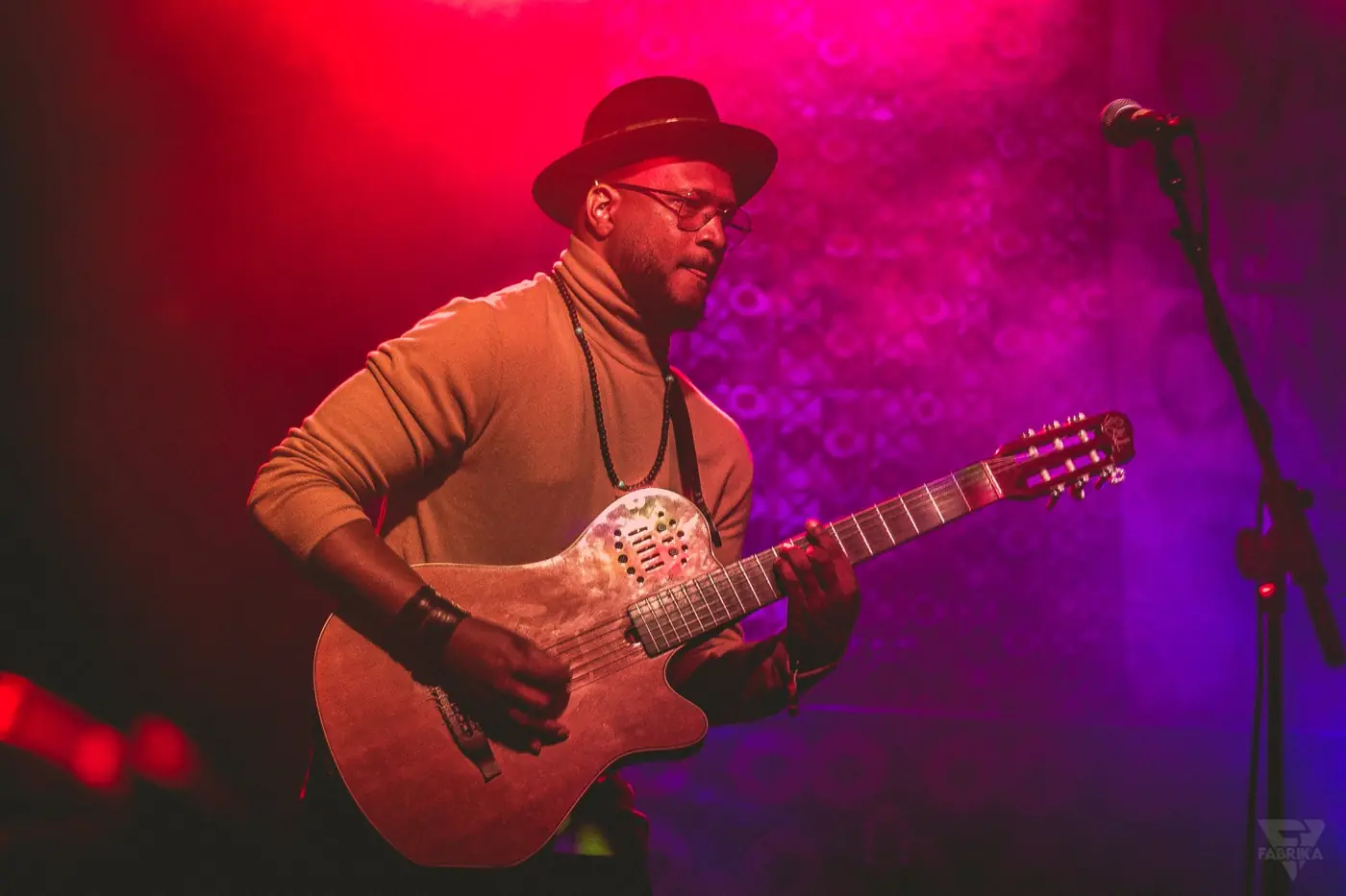 Guitarrista em palco sob luz vermelha e roxa