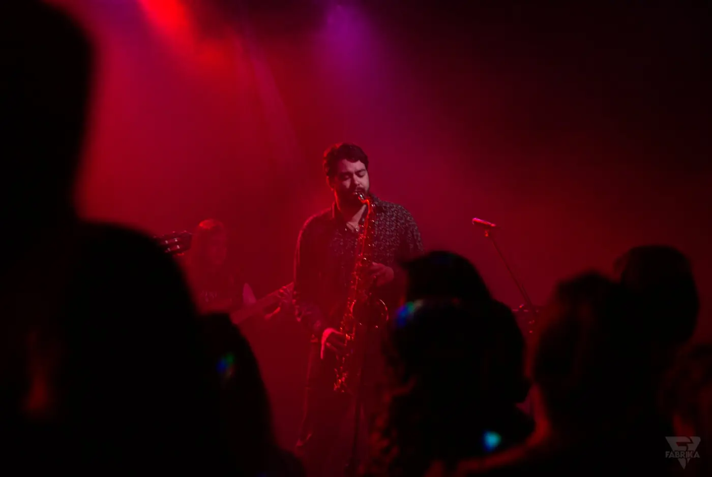 Saxofonista em palco envolto em luz vermelha